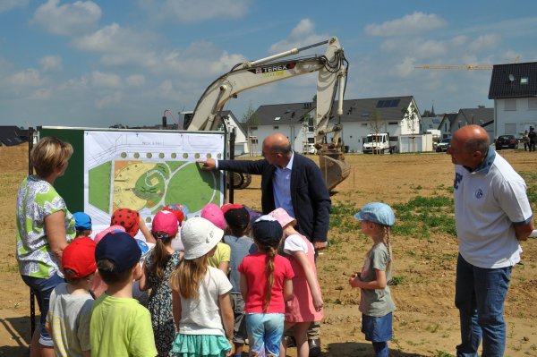 Foto zeigt Bürgermeister Bert Spilles mit den Kindern der Kita Löwenzahn an der Baustelle.