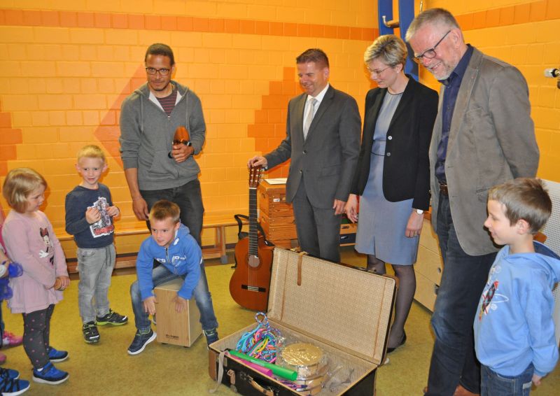 Foto zeigt die Akteure, unter ihnen der Erste Beigeordnete Holger Jung, und die Kita Kinder, die die neuen Instrumente ausprobieren.