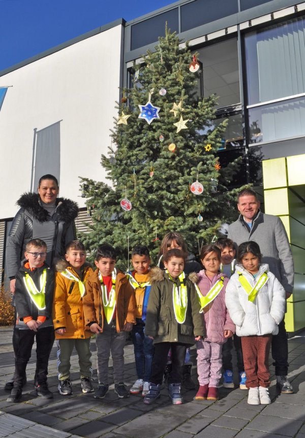 Foto zeigt Bürgermeister Holger Jung mit den Kita-Kindern vor dem geschmückten Weihnachtsbaum.