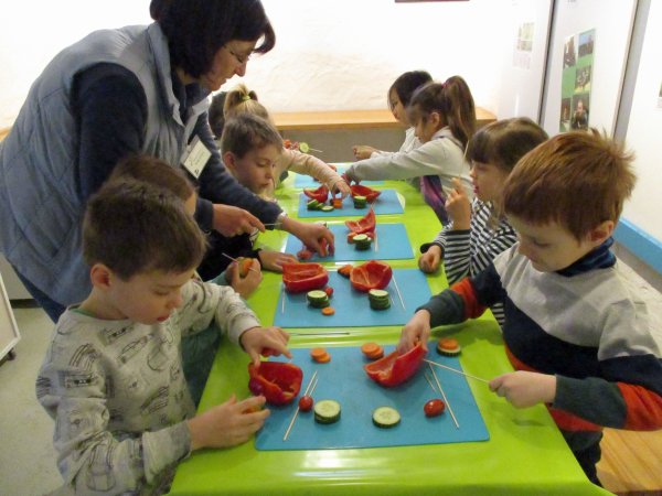 Foto zeigt die mit Gemüse beschäftigten Vorschulkinder und Mareike Czerwinski 
