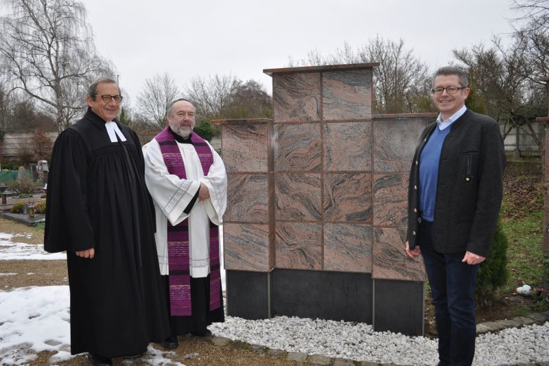 Foto zeigt diebeiden Pfarrer und den Ersten Beigeordneten Hans Dieter Wirtz vor der neuen Urnenwand.