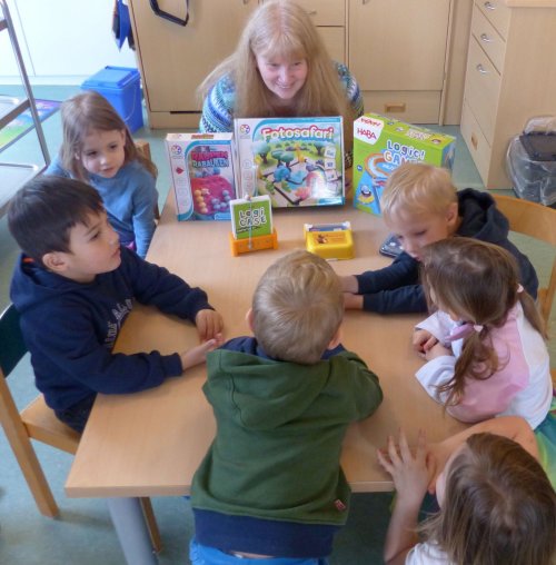 Foto zeigt Kita-Kinder und Tanja Muck am Spieltisch.