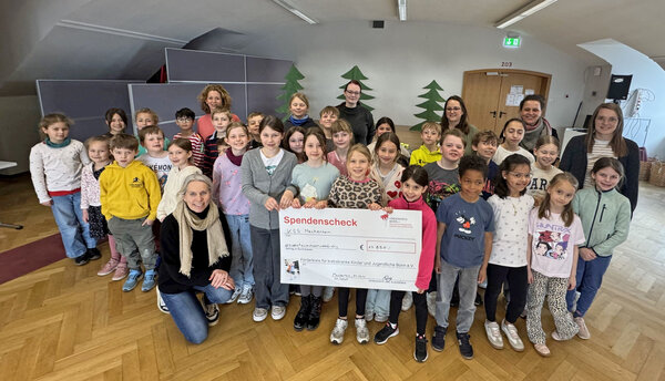 Die Beteiligten der Spendenübergabe haben sich um den Spendenscheck platziert.