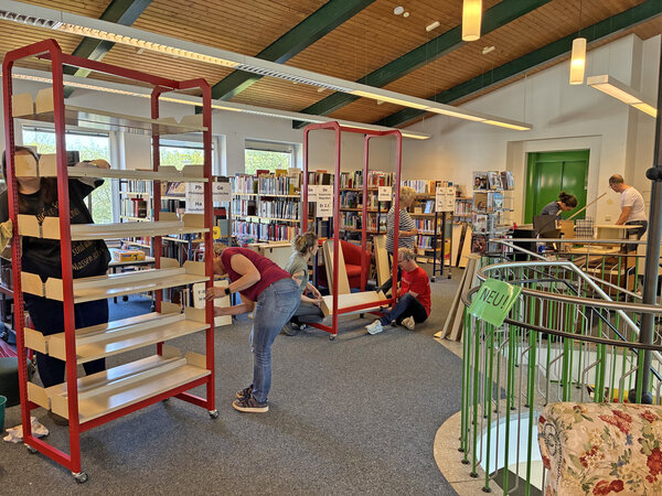 Helferinnen und Helfer bauen Regale auf.
