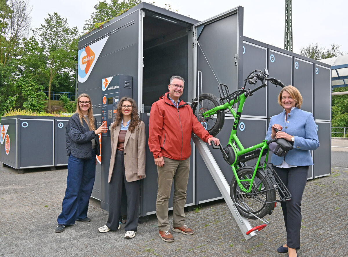 Die Beteiligten der Inbetriebnahme stehen vor einer der geöffneten Fahrradboxen mit E-Bike. 