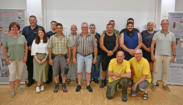 Die Beteiligten der Schulung stehen und knien vor einer Wand.