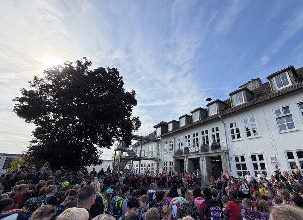Bild vergr&ouml;&szlig;ern: Zum Abschluss versammelten sich alle Kinder und Mitarbeitenden der KGS Meckenheim auf dem Schulhof. Beim gemeinsamen Singen ließen sie den Tag der offenen Tür ausklingen.