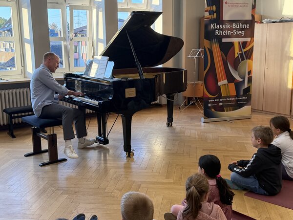 Bild vergr&ouml;&szlig;ern: Pianist Markus Kreul am Flügel beim musikalischen Erlebnis „Zauberkasten Klavier“ in der Katholischen Grundschule Meckenheim. Als Musiker und Moderator führte er durch das 45-minütige Programm