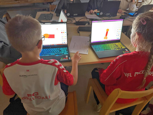 Zwei Kinder sitzen vor dem Laptop.